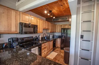 a kitchen with wooden cabinets and black appliances at St Francis #53 By Hauserman Rentals in Tahoe City