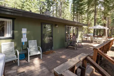 a large wooden deck with chairs and an umbrella at Squirrels Nest By Hauserman Rentals in Carnelian Bay