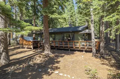 a green cabin in the woods with trees at Squirrels Nest By Hauserman Rentals in Carnelian Bay