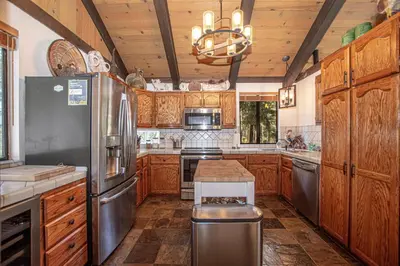 a kitchen with wooden cabinets and a stainless steel refrigerator at Thunder Lodge By Hauserman Rentals in Homewood