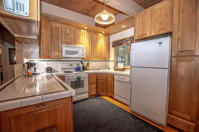 a kitchen with wooden cabinets and a white refrigerator at Willow By Hauserman Rentals in Tahoe City