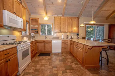 a large kitchen with wooden cabinets and white appliances at Knobcone Cabin by Hauserman Rental Group in Tahoma