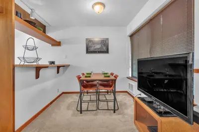 a living room with a table and a large flat screen tv at Cozy Condo with Fireplace - Tamarack 3 in Bear Valley