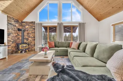 a living room with a green couch and a large window at Prasad Retreat - Sunny Home with Deck & Air Hockey home in Arnold