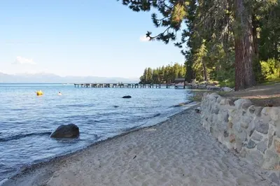 a beach with a stone wall next to a body of water at Tahoma Family Home in Tahoma