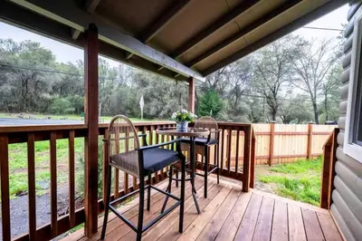 a patio with two chairs and a table on a deck at Columbia Cabins Cabin 1 in Sonora