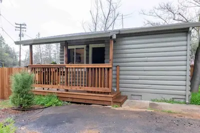 a small house with a large deck with a porch at Columbia Cabins Cabin 1 in Sonora