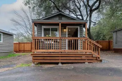 a small house with a large wooden deck at Columbia Cabins Cabin 3 in Sonora