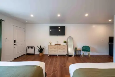 a bedroom with two beds and a dresser with a tv on the wall at Columbia Cabins Cabin 9 in Sonora