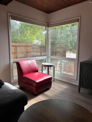 a living room with a red chair and a large window at Sam's Place Mariposa - In Town! in Mariposa