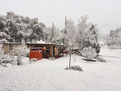 a house covered in snow in a yard at Sam's Place Mariposa - In Town! in Mariposa