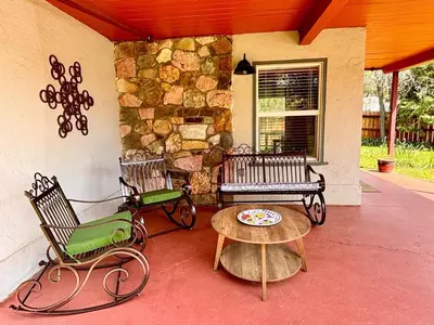 a porch with benches and a table and a stone wall at Sam's Place Mariposa - In Town! in Mariposa