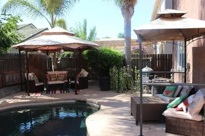 a backyard with a pool with umbrellas and a table and chairs at Luxurious 5-Bedroom Retreat with Saltwater Pool and Spa in Elk Grove