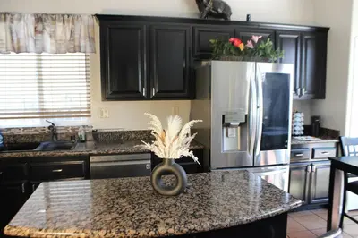 a kitchen with black cabinets and a granite counter top at Luxurious 5-Bedroom Retreat with Saltwater Pool and Spa in Elk Grove