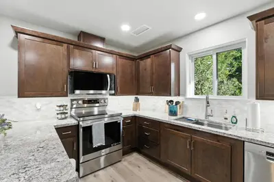 a kitchen with wooden cabinets and stainless steel appliances at The White House Coveted Triplex Near Lake