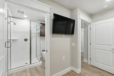 a bathroom with a shower and a tv on the wall at The White House Coveted Triplex Near Lake
