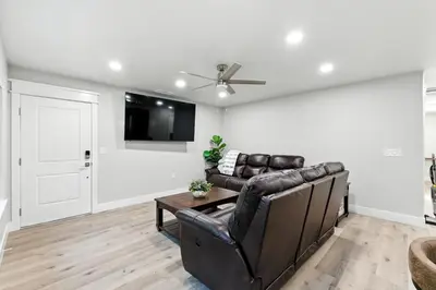 a living room with a leather couch and a tv at The White House Coveted Triplex Near Lake