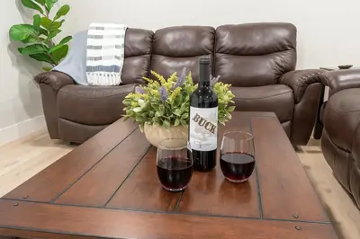 a bottle of wine and two glasses on a coffee table at The White House Coveted Triplex Near Lake