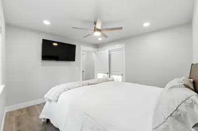 a white bedroom with a white bed and a ceiling fan at The White House Coveted Triplex Near Lake