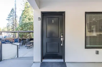 a black door on a white house at The White House Coveted Triplex Near Lake
