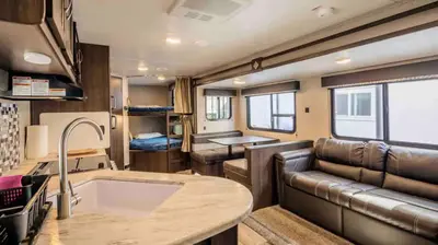 a kitchen and living room of an rv at Parked RV Travel Trailer Getaway Wi-Fi with Hookups in Fresno