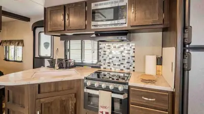 a kitchen with a stove and a sink in an rv at Parked RV Travel Trailer Getaway Wi-Fi with Hookups in Fresno