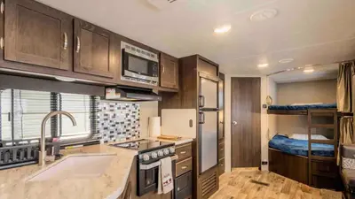 a kitchen with a sink and a kitchen with a bed at Parked RV Travel Trailer Getaway Wi-Fi with Hookups in Fresno