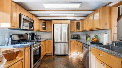 a kitchen with wooden cabinets and a stainless steel refrigerator at Year-Round Tahoe Escape with Hot Tub Outdoor Dining Timberline Haven by AvantStay in Tahoe Vista