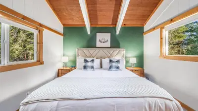 a bedroom with a large bed with two windows at Year-Round Tahoe Escape with Hot Tub Outdoor Dining Timberline Haven by AvantStay in Tahoe Vista