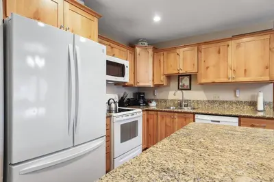 a kitchen with wooden cabinets and a white refrigerator at 2 Bedroom Kirkwood Condo – Across the Street from Village condo in Kirkwood