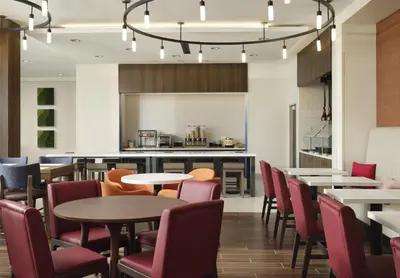 a restaurant with tables and chairs and a kitchen at Hilton Garden Inn Merced in Merced