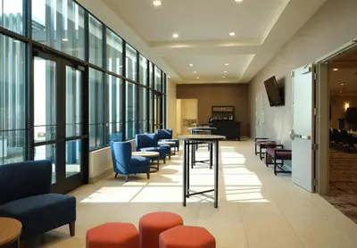 a lobby with chairs and a table and windows at Hilton Garden Inn Merced in Merced