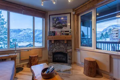 a living room with a fireplace and windows at Juniper Springs Lodge # 426 in Mammoth Lakes