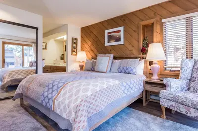 a bedroom with a large bed and a chair at Snowcreek #474 in Mammoth Lakes