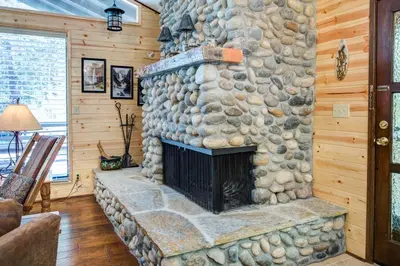 a stone fireplace in a living room with wooden walls at 42A Megan in North Wawona