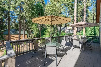a deck with tables and chairs and umbrellas at Leisure Landing Unwind in the Pines in Shaver Lake
