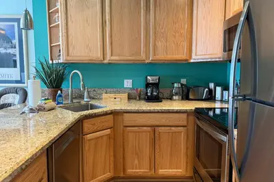 a kitchen with wooden cabinets and a refrigerator at Renovated Mountain Getaway, AC, Spa, Pool, Full Kitchen in Mammoth Lakes