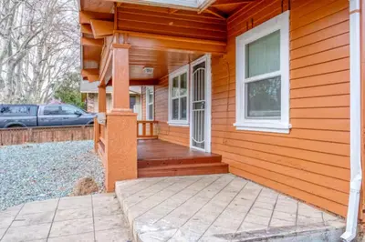 a wooden house with a porch and a car parked at 2BR Family Getaway with Yard Kitchen and Parking in Lodi