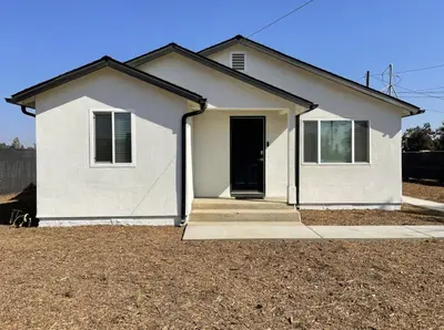 a white house with a door in a yard at Country Living 3BR with fenced yard on Mooney in Visalia