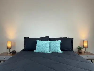 a bed with two blue pillows and two lamps at Cozy Entire Home Gateway to Sequoia Pet Friendly in Visalia