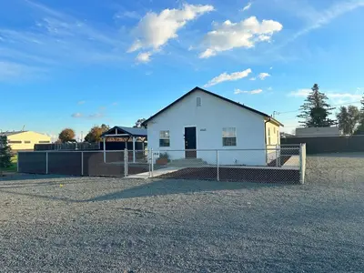 a white house with a fence in front of it at Sequoia Basecamp With Fenced Yard in Visalia