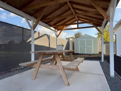 a picnic table under a pavilion with a shed at Sequoia Basecamp With Fenced Yard in Visalia