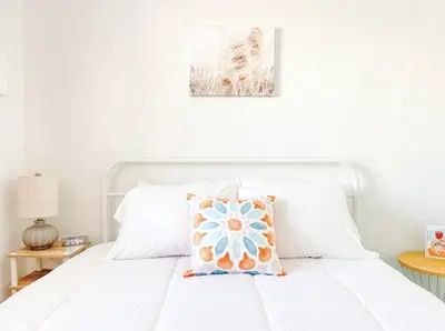 a white bed with a flower pillow on it at Lovely home central Coalinga-2BR Stopover near I-5 in Coalinga