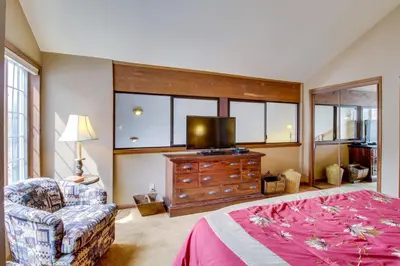 a bedroom with a bed and a tv and a chair at Sierra Megeve 13 in Mammoth Lakes