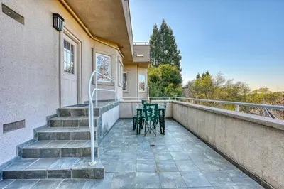 a balcony with two chairs and stairs on a building at Vista De Lago Retreat Luxury Mansion with Pool and Theater in Granite Bay