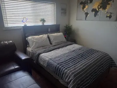 a bedroom with a bed with a blue headboard and a window at Franklin Apt in Fresno