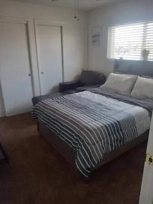 a bedroom with a bed with a blue and white striped blanket at Franklin Apt in Fresno