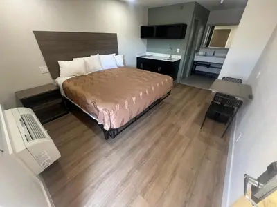 a small hotel room with a bed and a sink at Value Suites Extended Stay in Sacramento