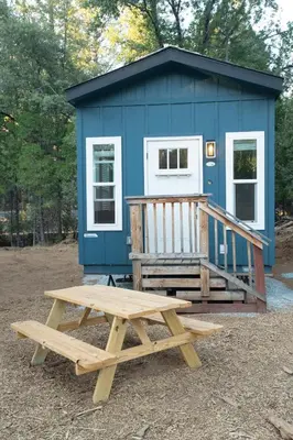 a picnic table in front of a blue tiny house at Tiny Blue at Yosemite Gateway in Groveland