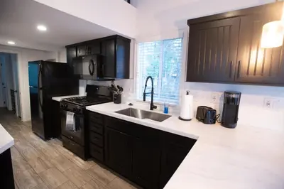 a kitchen with black cabinets and a sink at Tiny Blue at Yosemite Gateway in Groveland